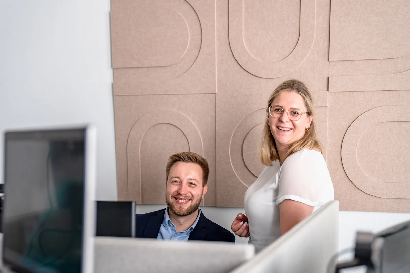 Zwei Mitarbeitende von Cogitaris lachen in die Kamera am Arbeitsplatz des Marktforschungsinstituts in Mainz